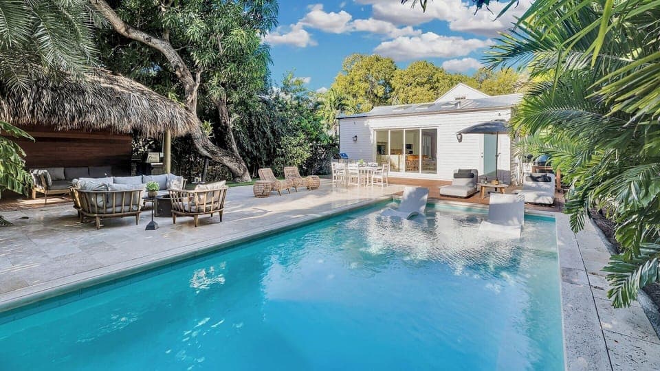 Your tropical oasis awaits with crystal-clear pool waters reflecting swaying palms, cozy thatched lounge, and modern villa surrounded by lush greenery.