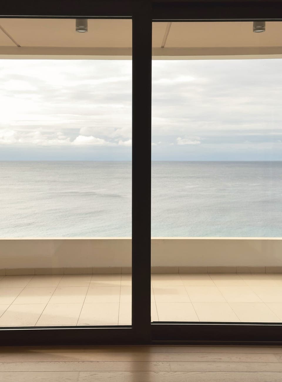 Master bedroom sea view framed by glazed sliding doors and terrace edge