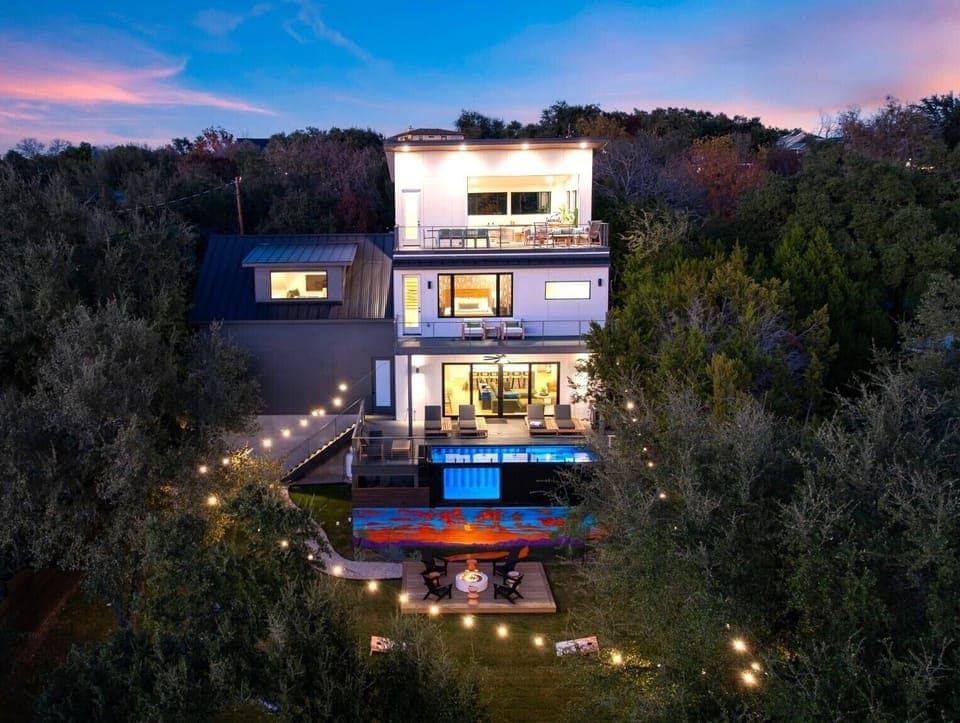 Austin nights shine at this multi-level retreat, with glowing decks, a private pool, and sunset views framed by the trees.