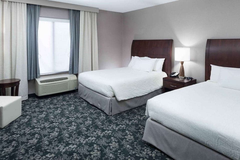 Two queen beds with soft linens and bedside lighting