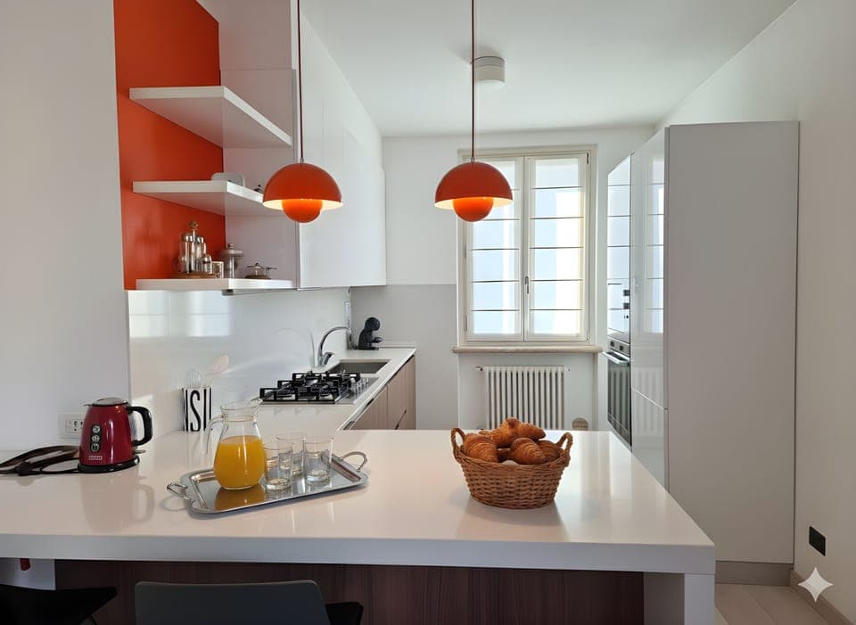 Modern and bright kitchen in the apartment located in Peschiera del Garda, equipped with a central island and fully equipped. The room has a stove, sink, appliances, and large countertops, ideal for preparing meals and enjoying convivial moments during your stay.