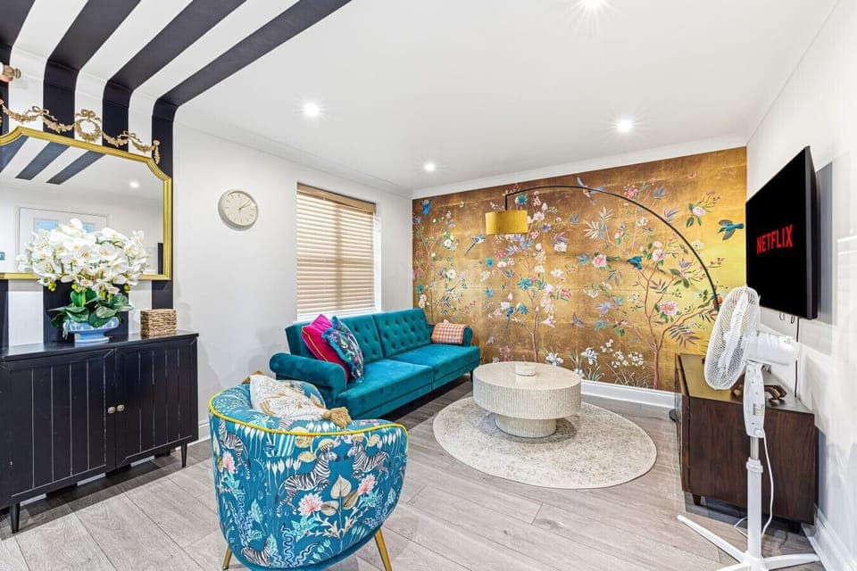 Stylish living room featuring a comfortable sofa, armchair, and a 50” Smart TV, perfect for relaxing and unwinding.