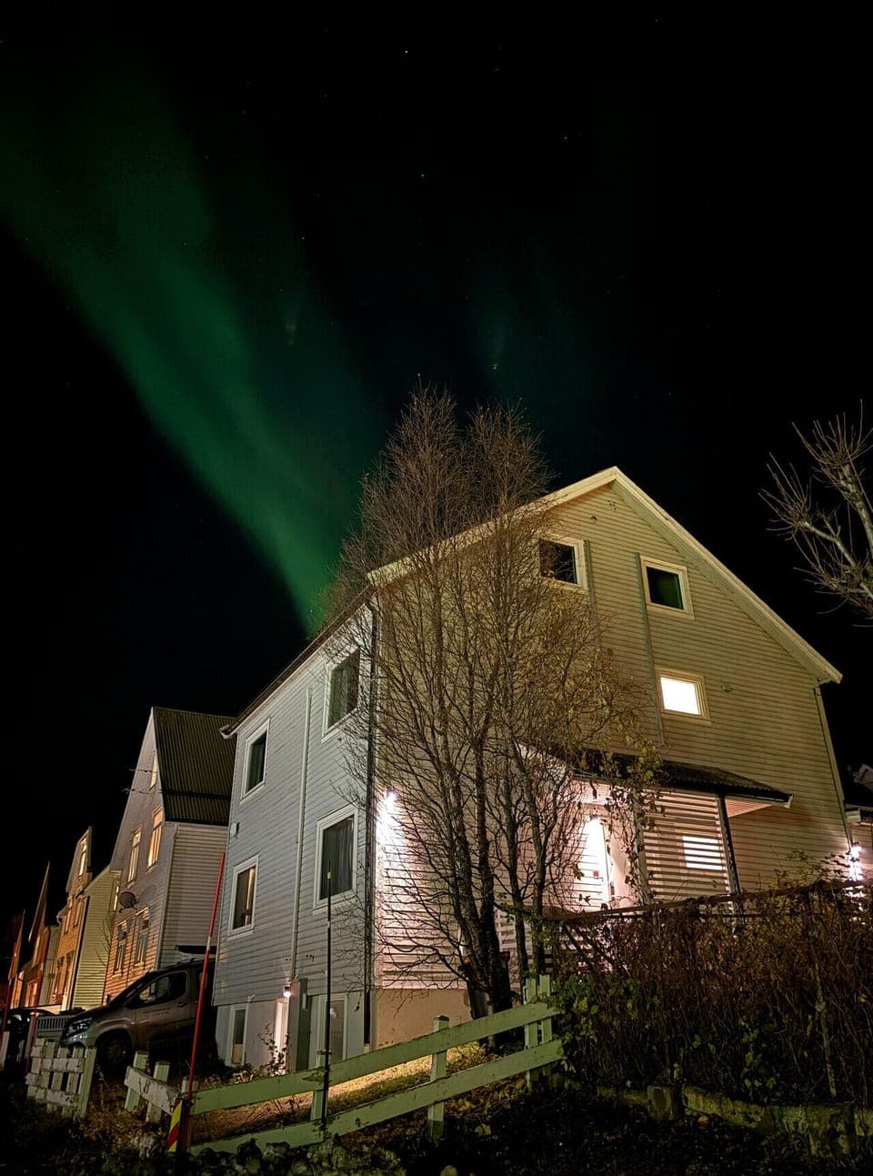 Bilde av fasaden med Nordlys over hustaket. Bilde fra oktober 2025.