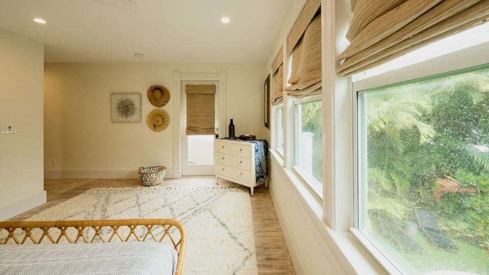 Relax in your peaceful bedroom sanctuary with natural light streaming through bamboo shades and lush tropical views outside...