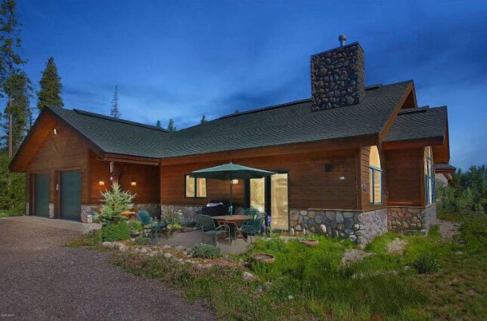 Rustic mountain lodge featuring natural stone and wood construction at evening twilight in the summer season