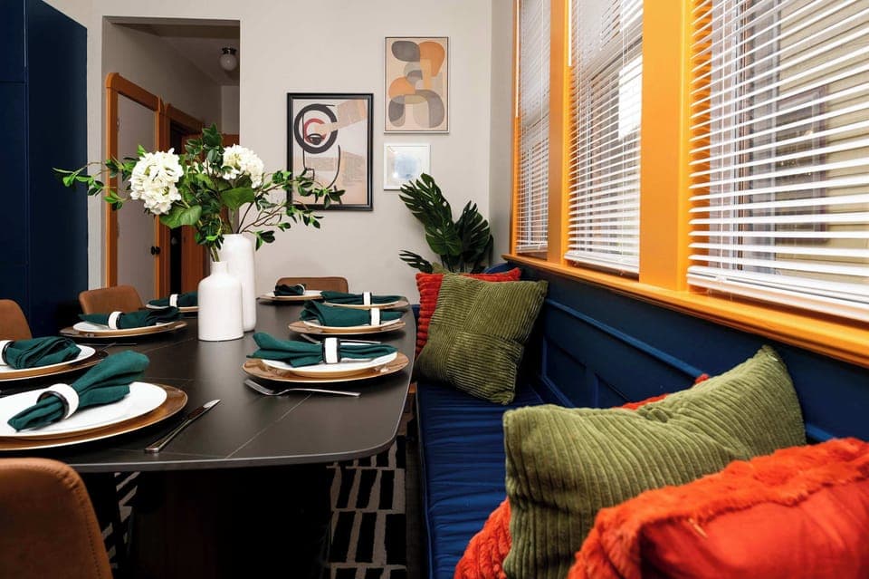 Bright dining nook with colorful pillows, modern table settings, and cozy bench seating—an inviting spot for group meals, game nights, and relaxed conversations