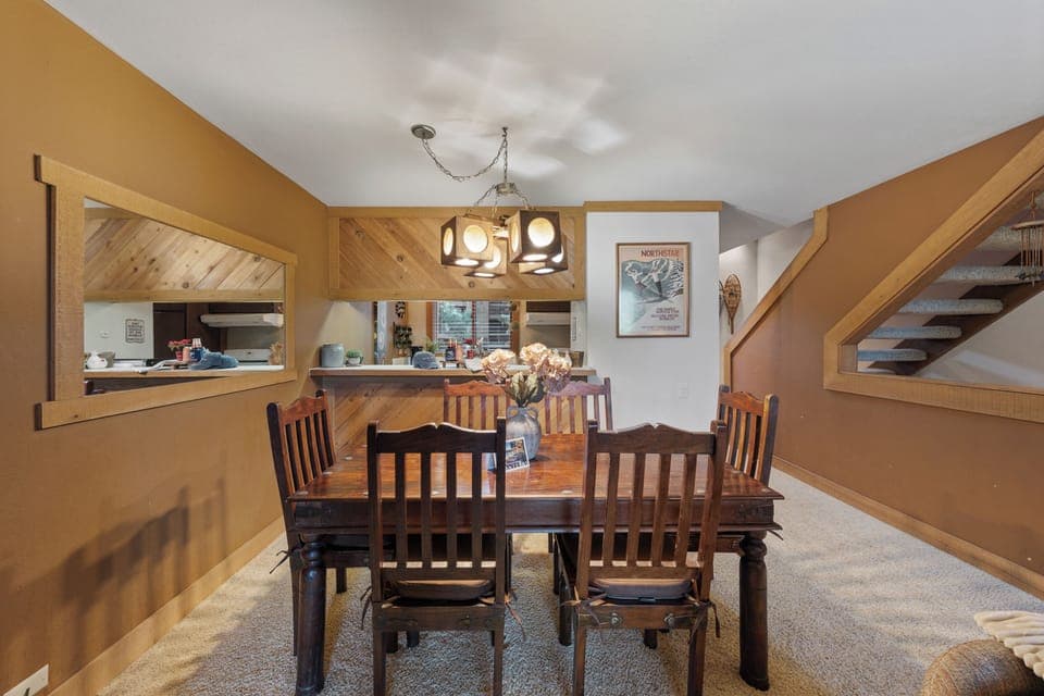 Cozy dining area with seating for six, warm cabin tones, and an open pass-through to the kitchen.
