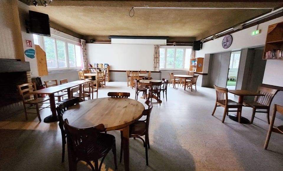 A comfortable lounge area with wooden tables and chairs, perfect for gathering and enjoying the warmth of the Jura mountain spirit.