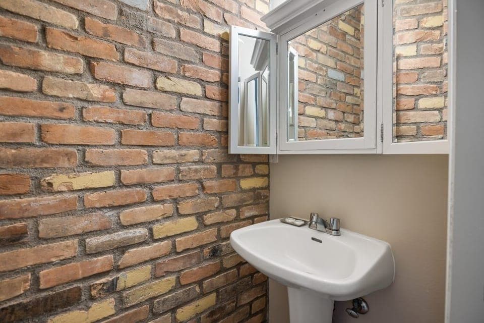 Freshen up quickly in a stylish half bath with brick accents.