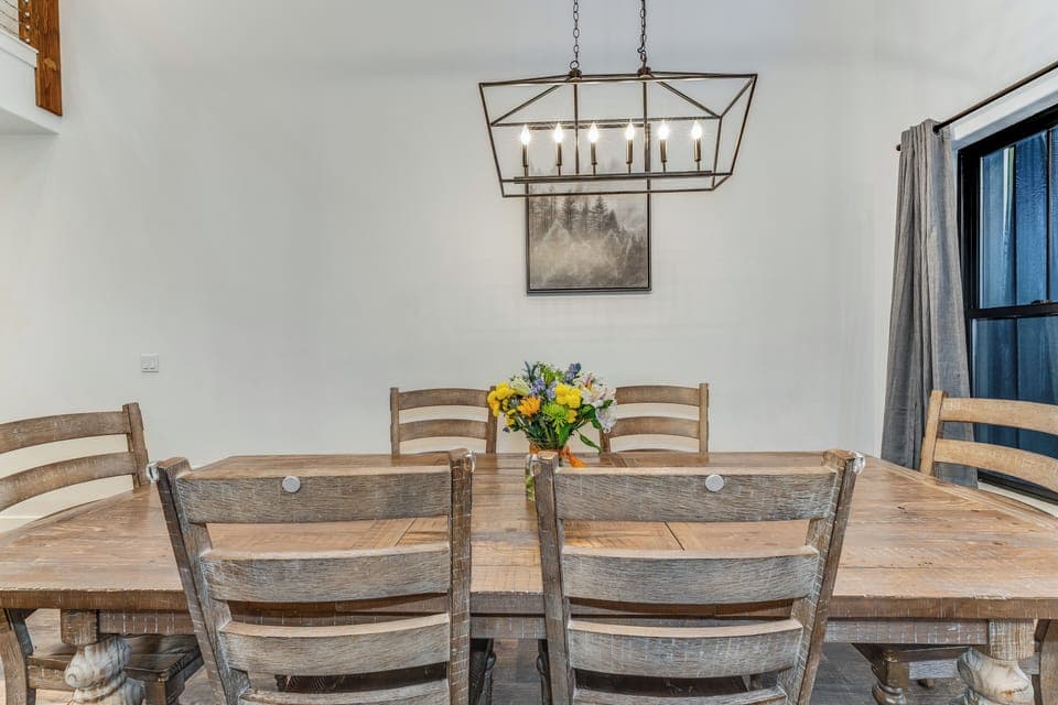 Gather around your rustic dining table for memorable meals beneath warm lantern lighting and peaceful mountain artwork.