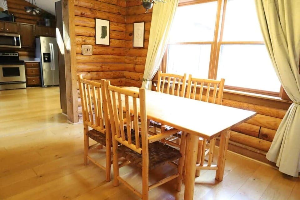 Charming log cabin dining nook with natural wood furniture and soft window light, ideal for cozy breakfasts or intimate dinners.