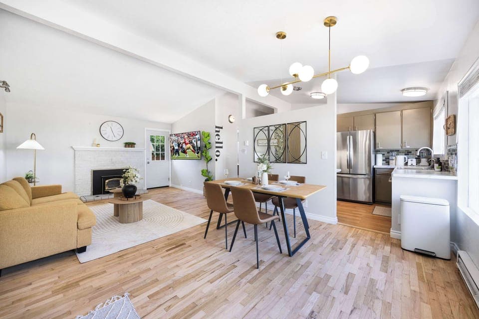 Golden pendant lights cast warm pools over honey-toned dining table where conversations linger