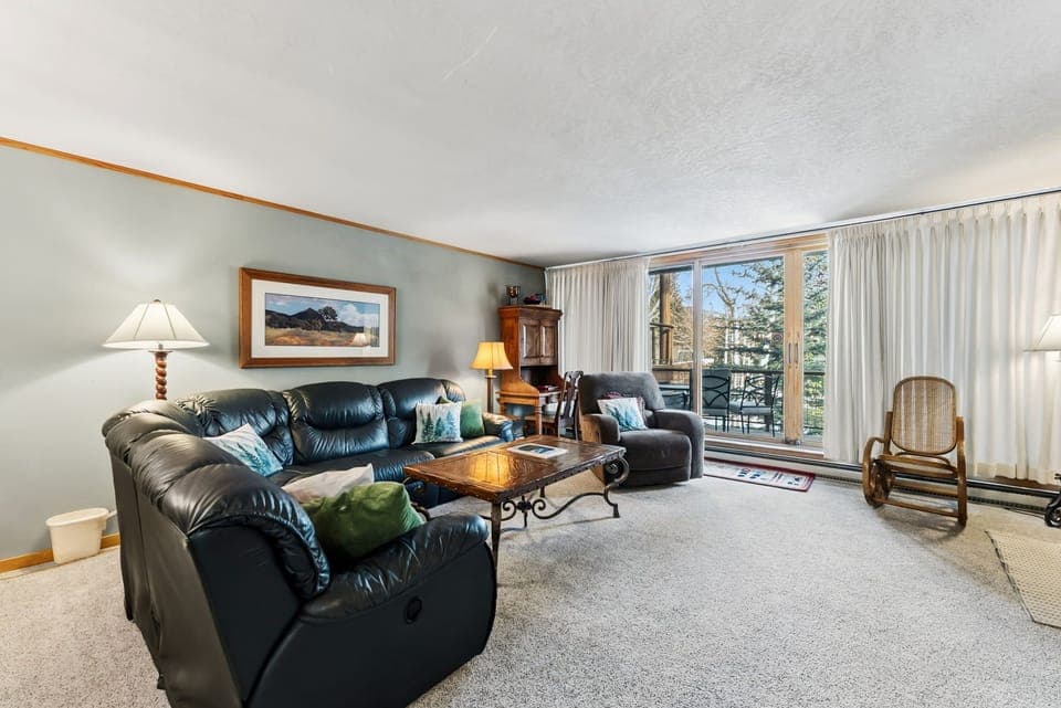 Sink into plush leather seating in your spacious living room, where large windows frame mountain views and natural light fills the space.