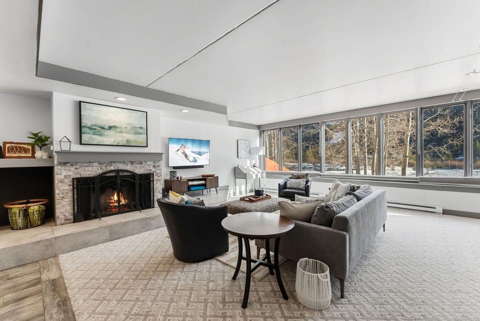Relax in your spacious living room with crackling fireplace and stunning natural views through floor-to-ceiling windows.