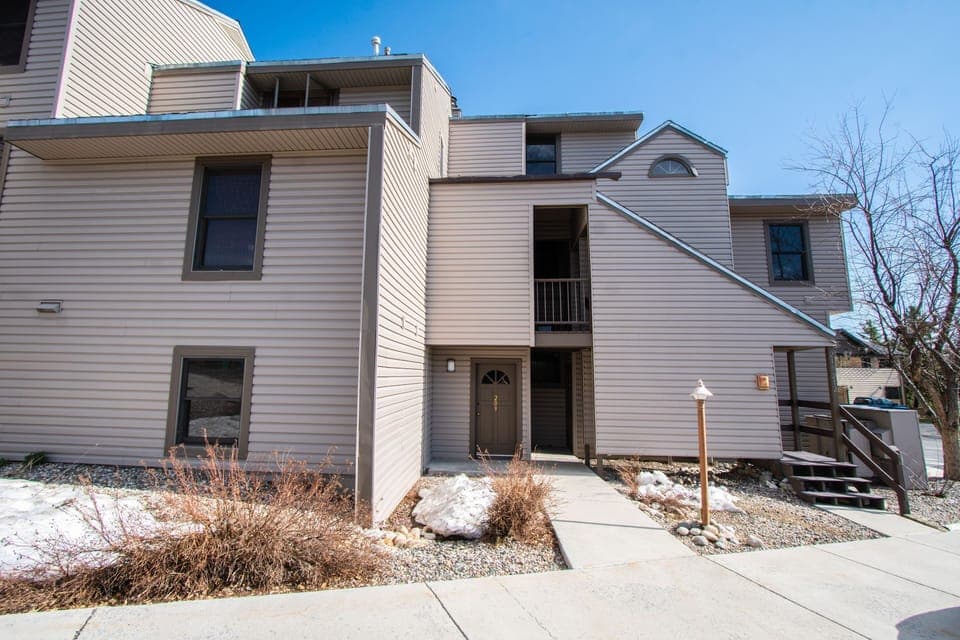 Two-story townhouse-style building with neutral siding and a welcoming front entry.