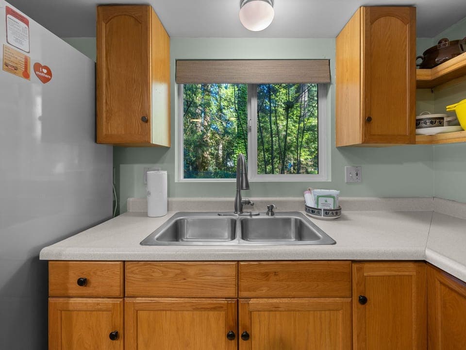 Your fully equipped kitchen overlooks lush forest views, perfect for preparing meals while enjoying nature's beauty outside your window.