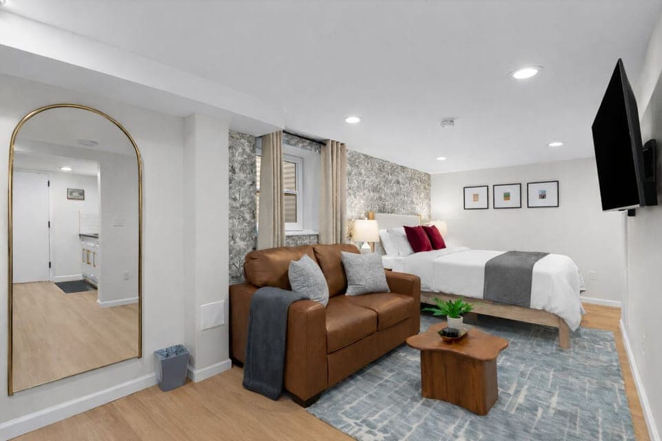 Bright, stylish studio with a plush bed, cozy seating area, smart TV, and warm finishes—designed for comfort, relaxation, and an easy stay.