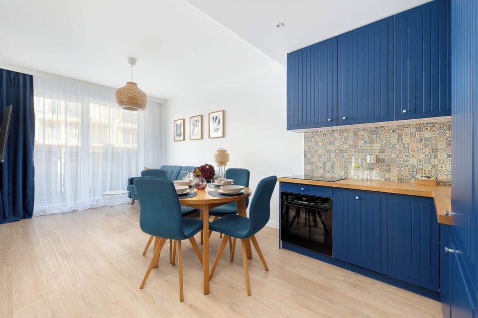 Stylish kitchen finished with blue cabinetry, patterned backsplash, and dining table.