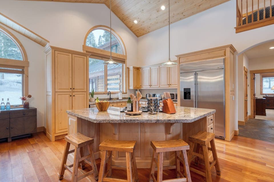 Your gourmet kitchen features a large refrigerator and a central island table.