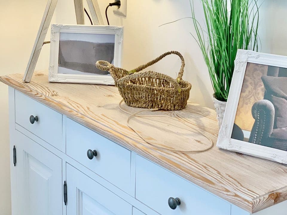 A sideboard with pictures and a decorative basket.