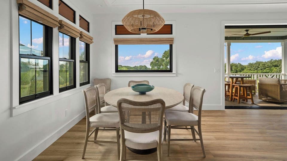 Gather around your beautiful dining table surrounded by windows showcasing peaceful countryside views through every frame.