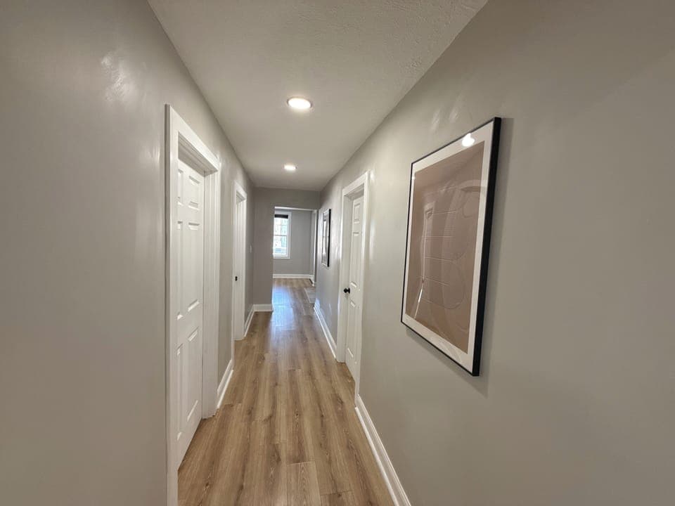 Clean, well-lit hallway connecting bedrooms and common areas. Neutral tones and recessed lighting create a calm, modern flow throughout the home.