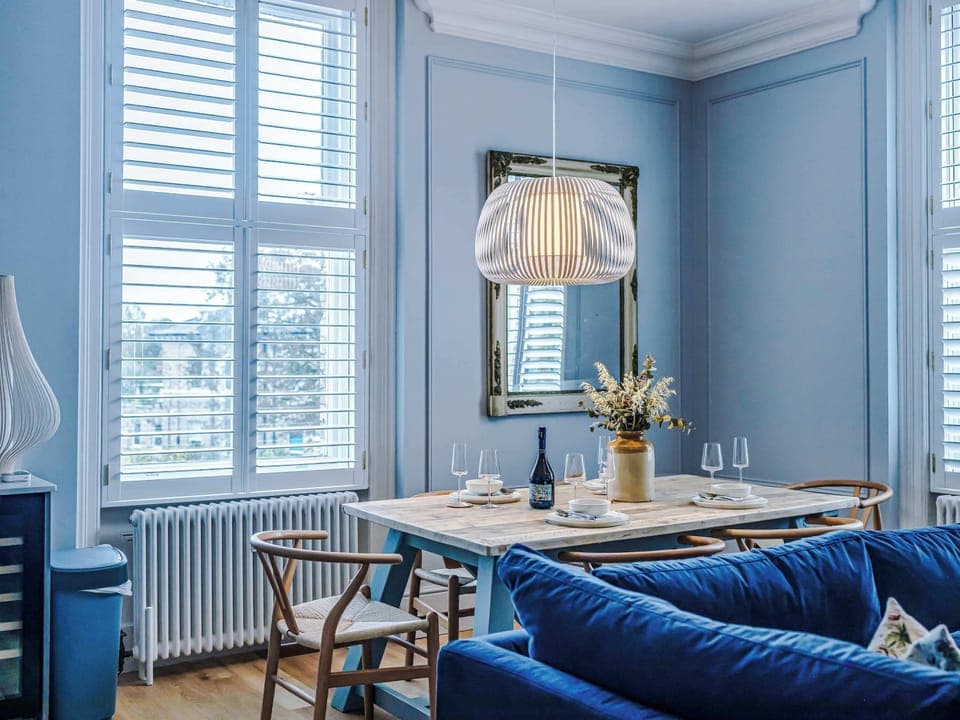 Bright and inviting living room with a navy sofa, large windows, and warm wood floors. Scandinavian-inspired décor blends modern style with comfort, creating a cozy space perfect for relaxing or entertaining in natural light.