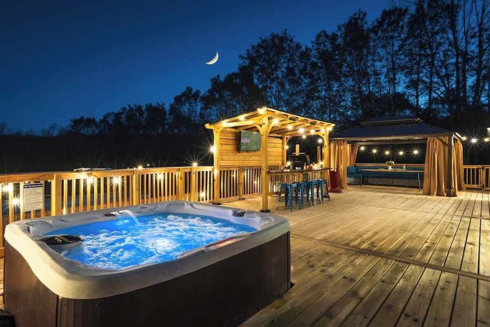 Unwind in the hot tub under the stars as the home glows beautifully at night.
