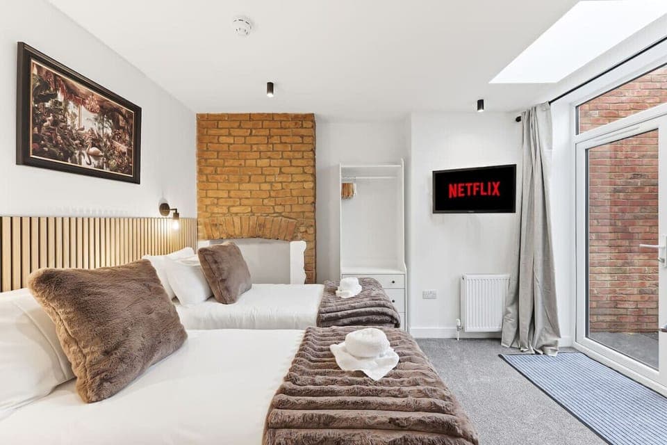 Bedroom One features a private patio, Smart TV, and a zip-and-link bed. The bed is configured as twin beds by default but can be converted into a king-size bed upon request.