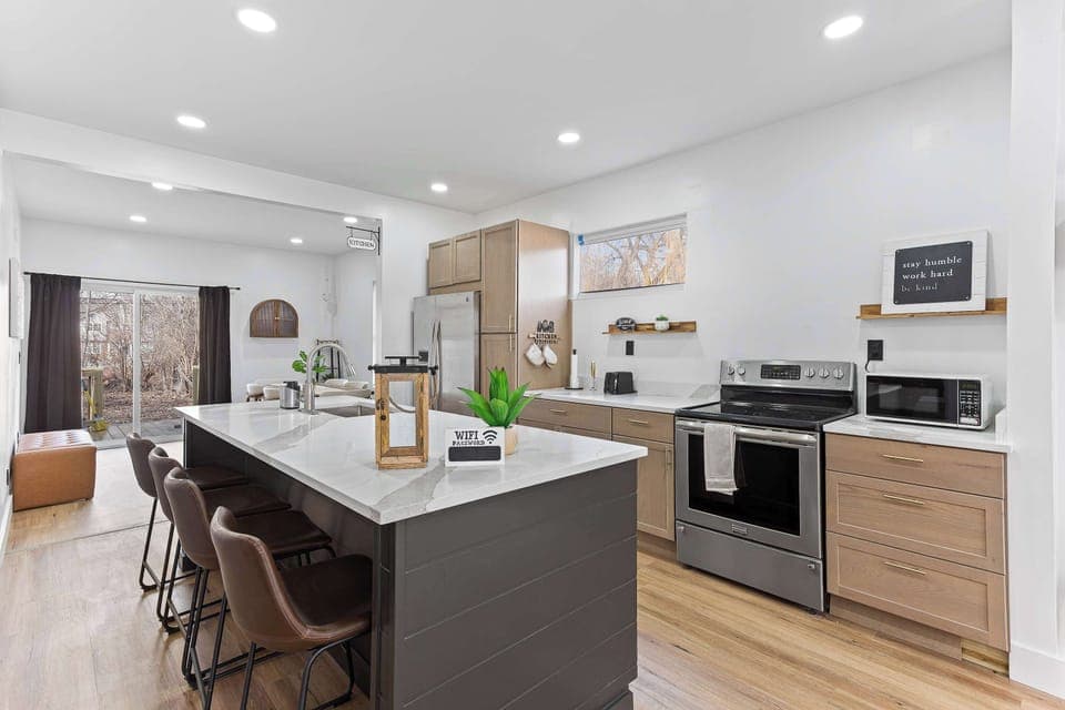 Modern kitchen with large island seating, stainless steel appliances, and open concept design. Perfect for cooking, entertaining, and gathering comfortably.