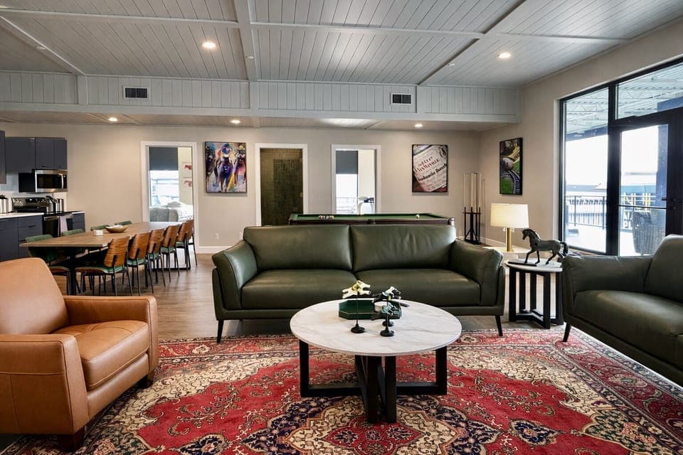 Sink right into the deep olive green sofa resting on a gorgeous oversized red patterned rug. The sleek round marble coffee table is perfect for holding your morning coffee or evening cocktails.