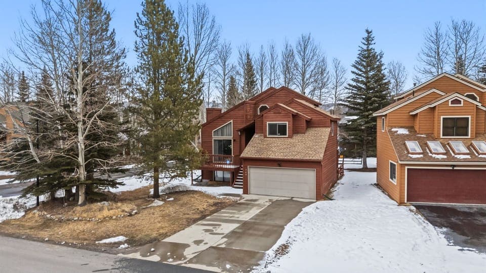 Cozy mountain cabin nestled among towering evergreens with convenient parking and winter charm in a peaceful wooded neighborhood.