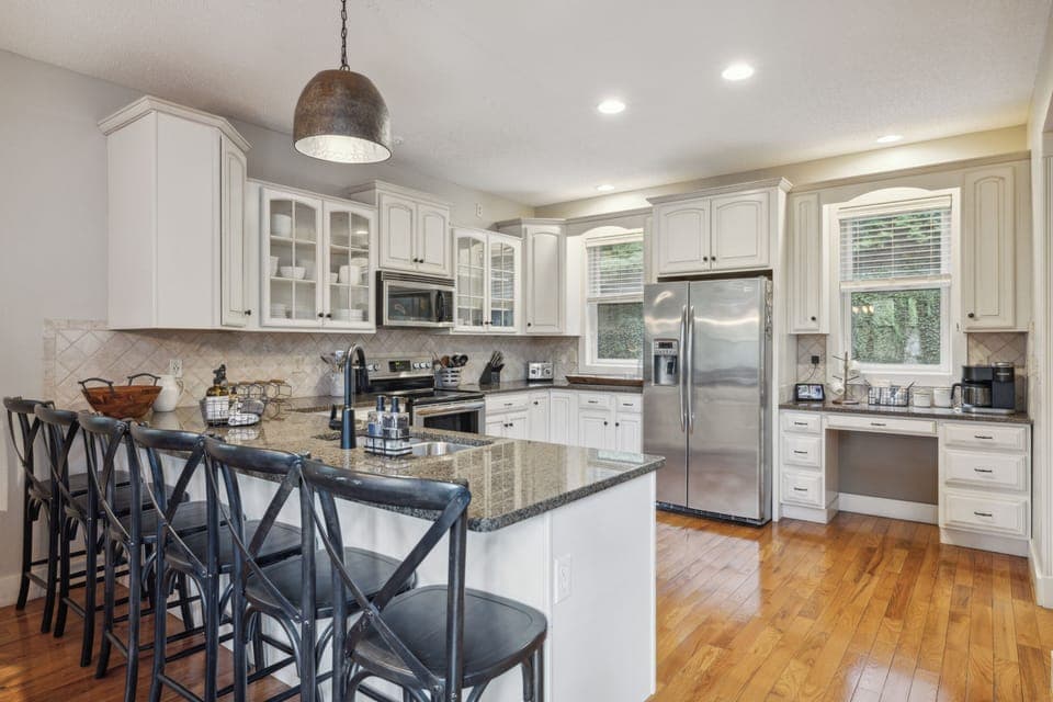 Bright, fully equipped kitchen with granite island and bar seating.