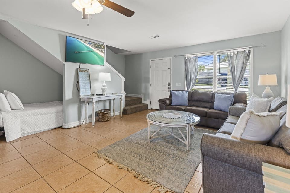 Unwind in your bright, coastal living room with plush seating, entertainment center, and serene ocean artwork to set your vacation mood.