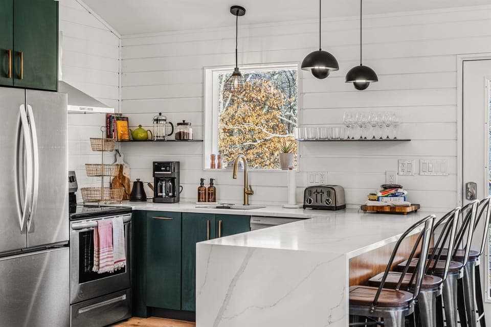 Our kitchen makes cooking and entertaining easy, with a roomy island, bar seating, green cabinets, and stainless steel appliances.
