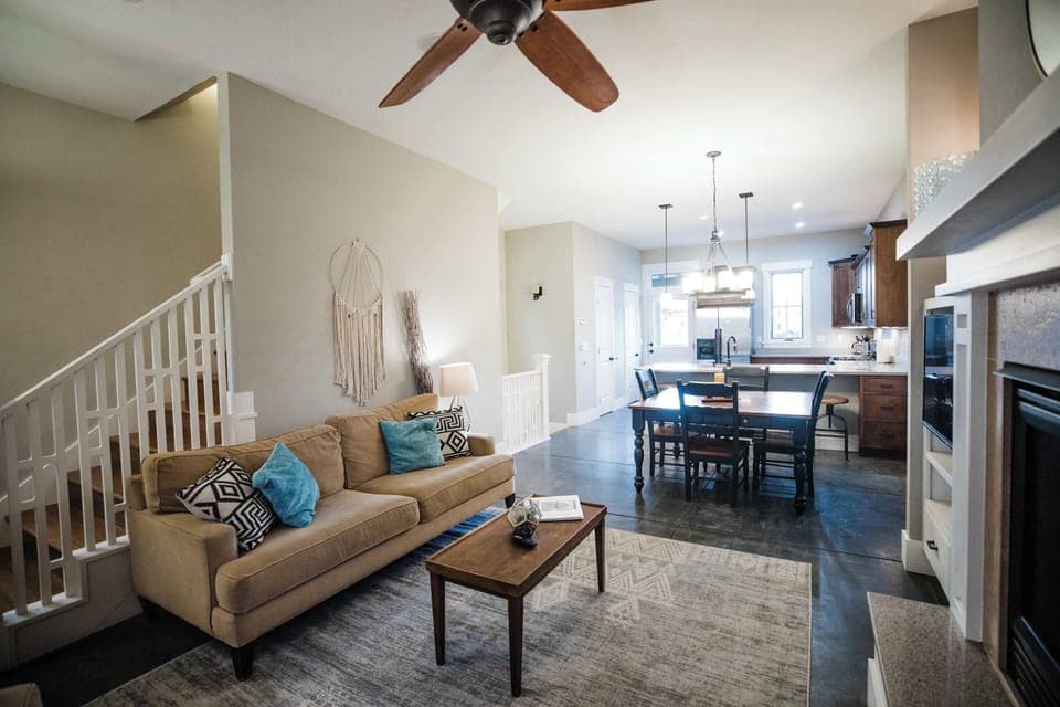 The open-concept main level flows from the living area through to the dining space and kitchen, anchored by warm wood tones, a ceiling fan, and an abundance of natural light.