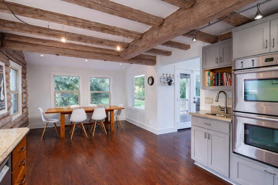 Open, airy dining space with rustic wood beams and garden views - perfect for gathering, lingering meals, and effortless indoor-outdoor living.