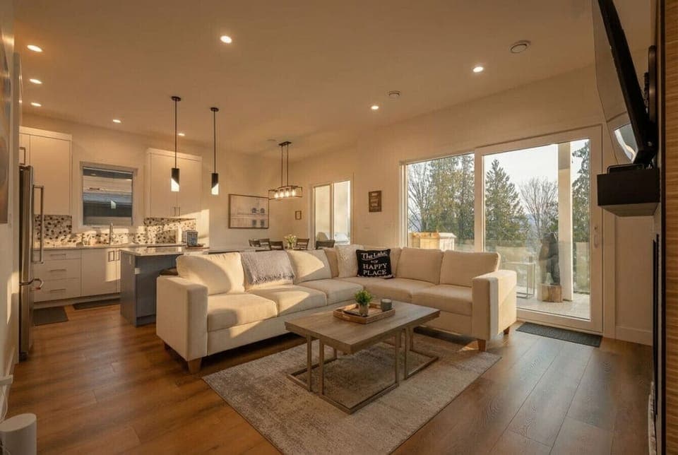 Main floor living room with an indoor fireplace, smart TV, cozy sectional, walkout access to the balcony`s outdoor seating & kitchen and glorious lake views.