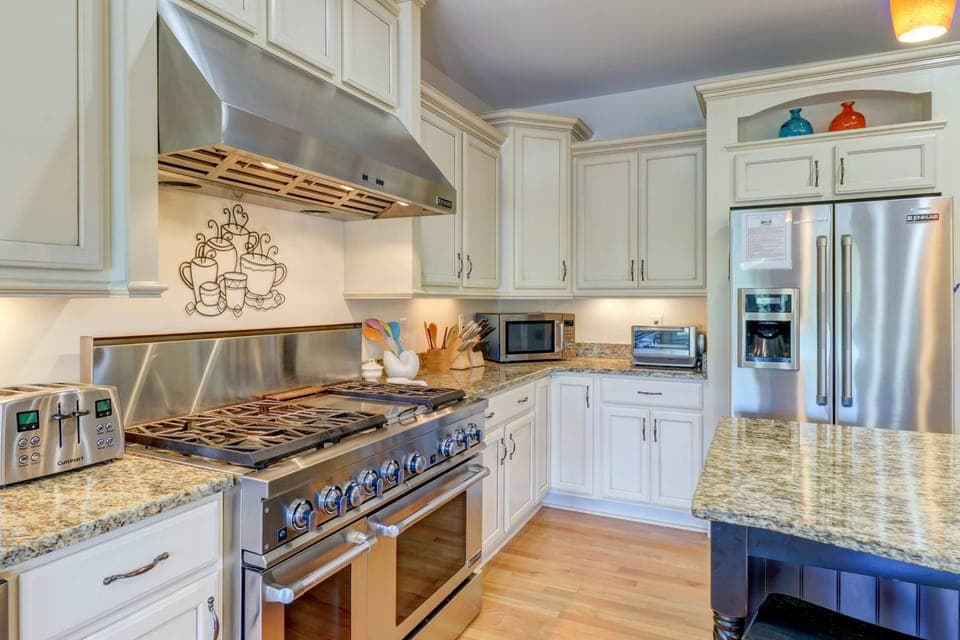 Kitchen - Chef-ready setup with an 8-burner gas range, vent hood, island, and stainless appliances.