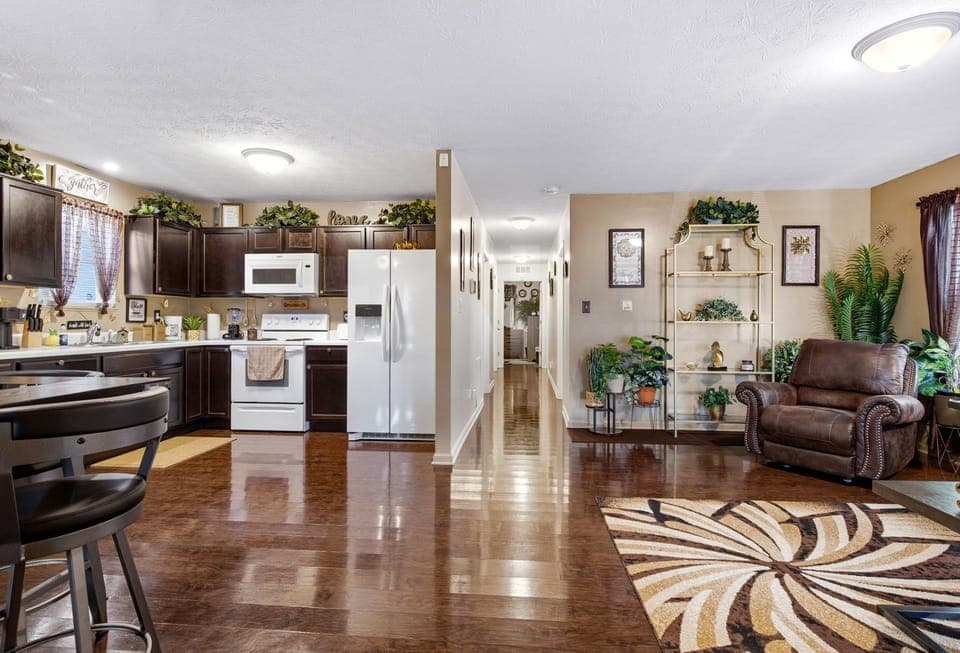 Open kitchen & cozy lounge with hardwood floors and lush plants.