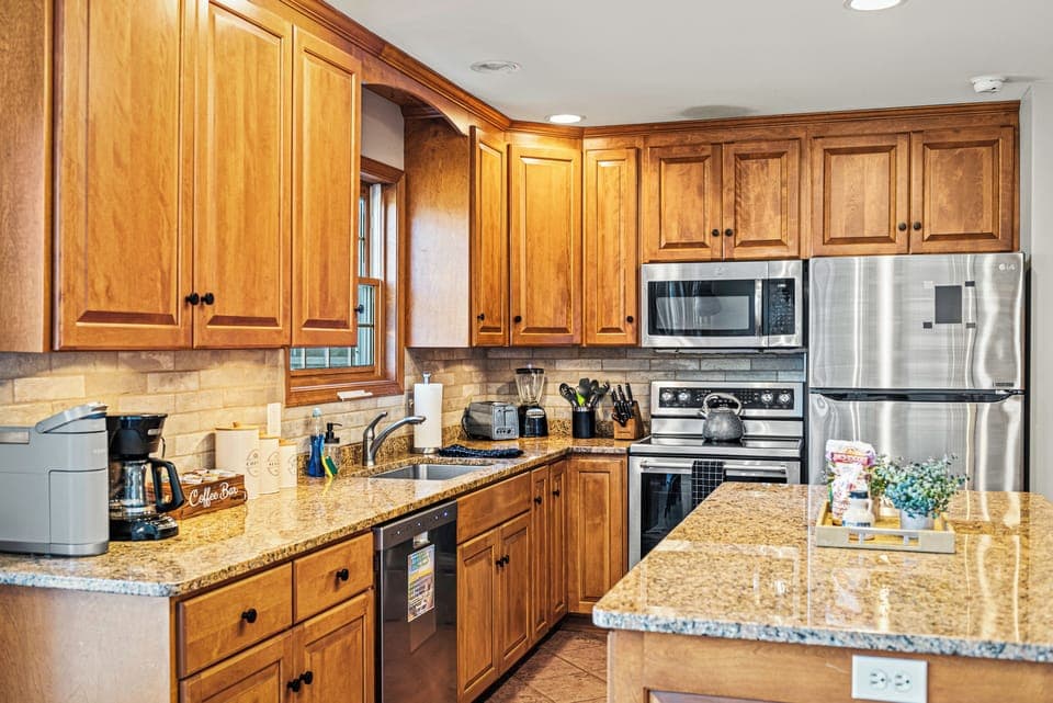 Warm wood‑toned kitchen with granite counters, stainless steel appliances, and a neatly organized island centerpiece. (Laker's Pointe)