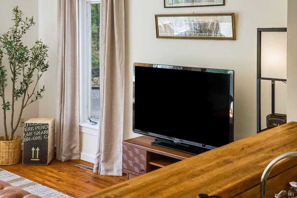 Entertainment corner featuring a large flat-screen TV on a mid-century modern console, complemented by stylish floor lighting and curated wall art.