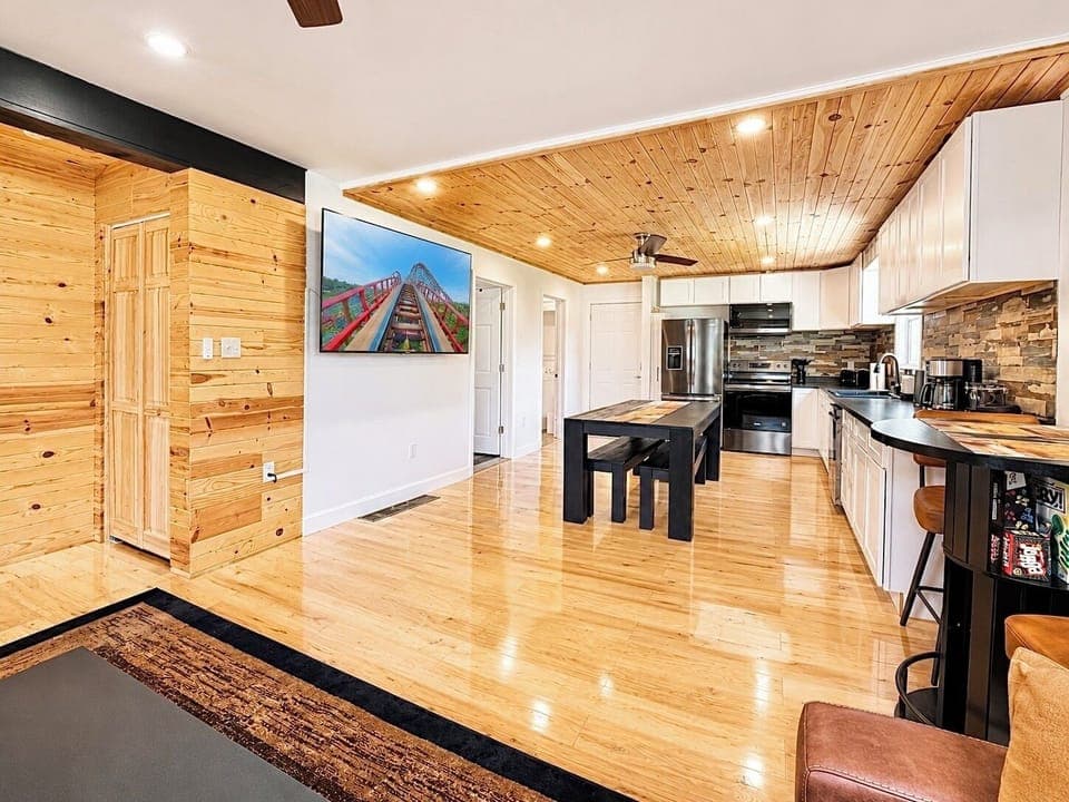 Open-concept living at its best—enjoy a spacious layout with warm wood accents, comfortable seating, and a large TV perfect for movie nights.