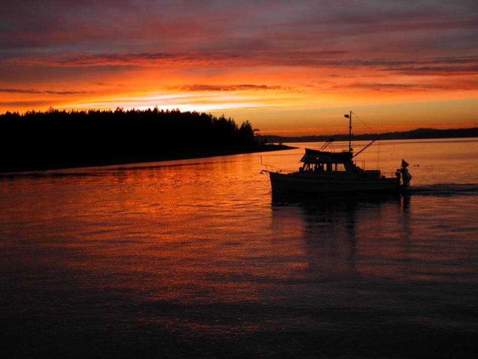 View from living room of a gorgeous sunset with a boat coming into the bay