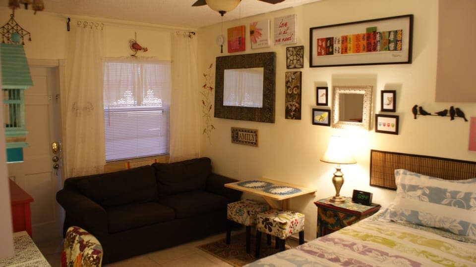 Queen size bed,sofa, wall mounted drop-leaf table and stools for dining.