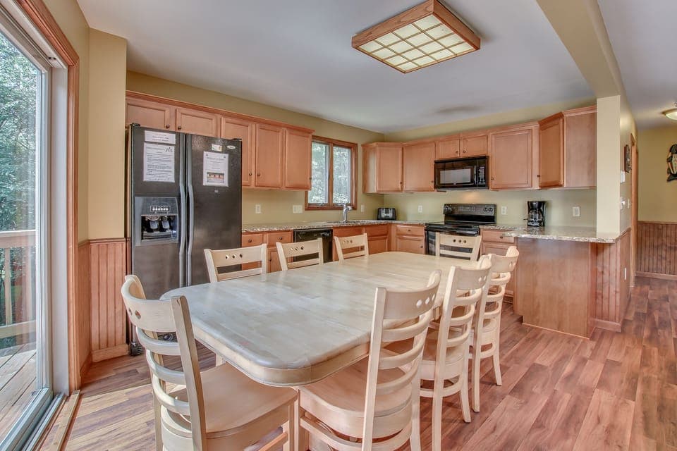 The kitchen with table and chairs, a double-door refrigerator, oven, and microwave.