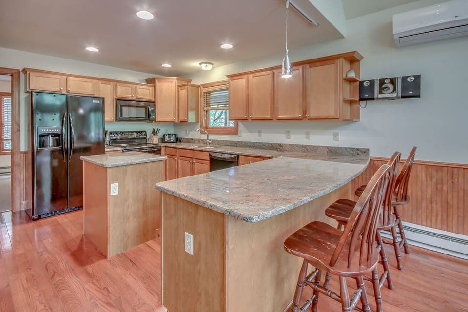 Kitchen with Counter, High Chairs, Refrigerator, Microwave, and A/C.