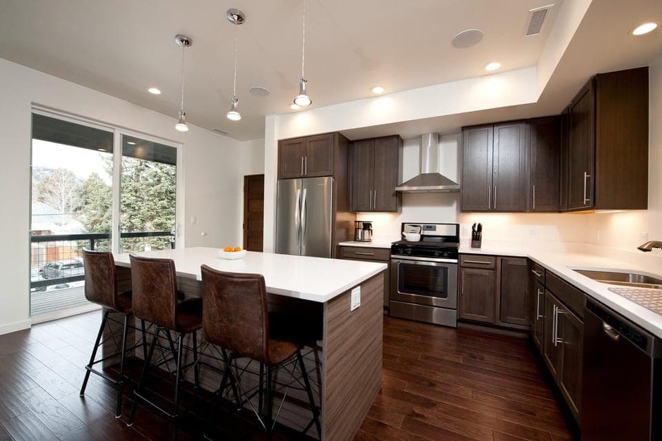 Kitchen with traditional drip coffee maker, fridge, stove, and oven. Island with bar stools.