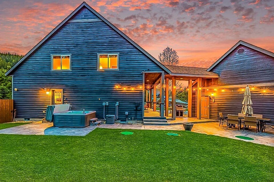 Twilight-lit backyard with a luxe hot tub, covered breezeway, and patio