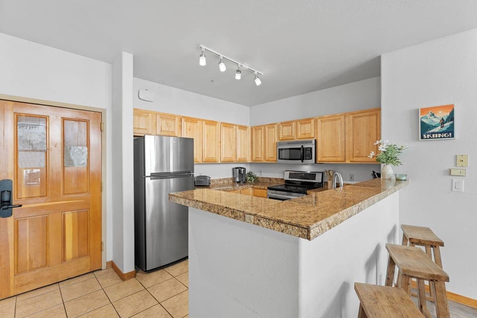 Full kitchen with stainless steel appliances and breakfast bar.